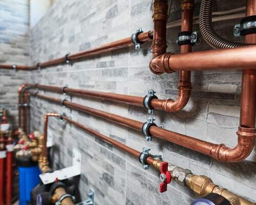 Copper plumbing lines installed cleanly along a tiled wall.