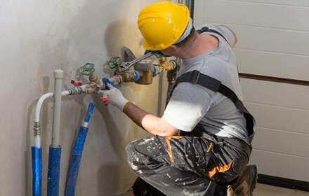 Plumber working on interior pipe connections.